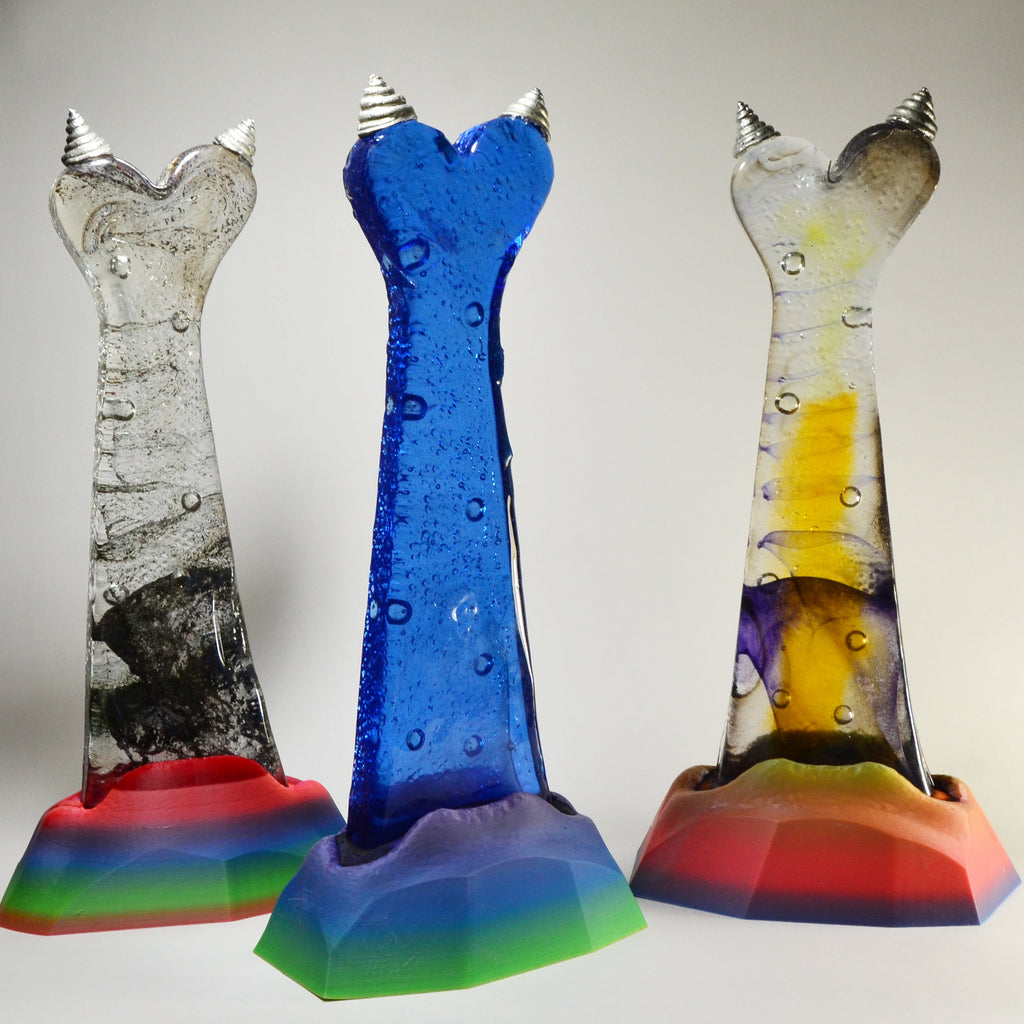 Three colorful glass sculptures on a plain background