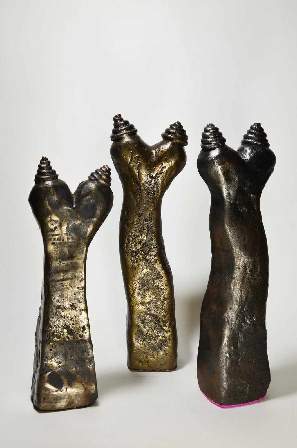 Three metallic sculptures resembling hands on a white background