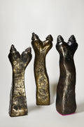 Three metallic sculptures resembling hands on a white background